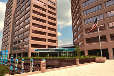 The exterior of an office building with two towers. The sign in front reads "state of Connecticut"