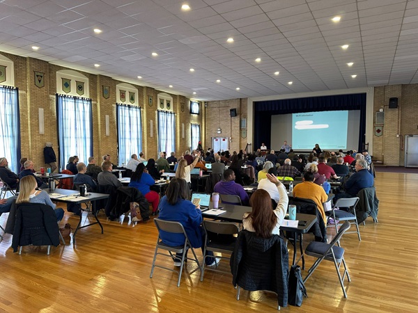 A person delivers a PowerPoint in a large room